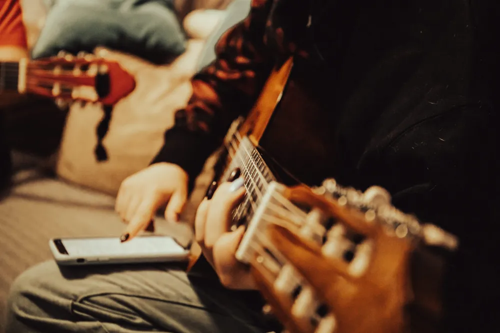 Guitarist referring to music on a phone while practicing
